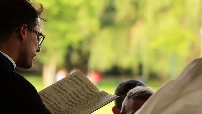 Symbolbild mit Pfarrer, der die Bibel liest